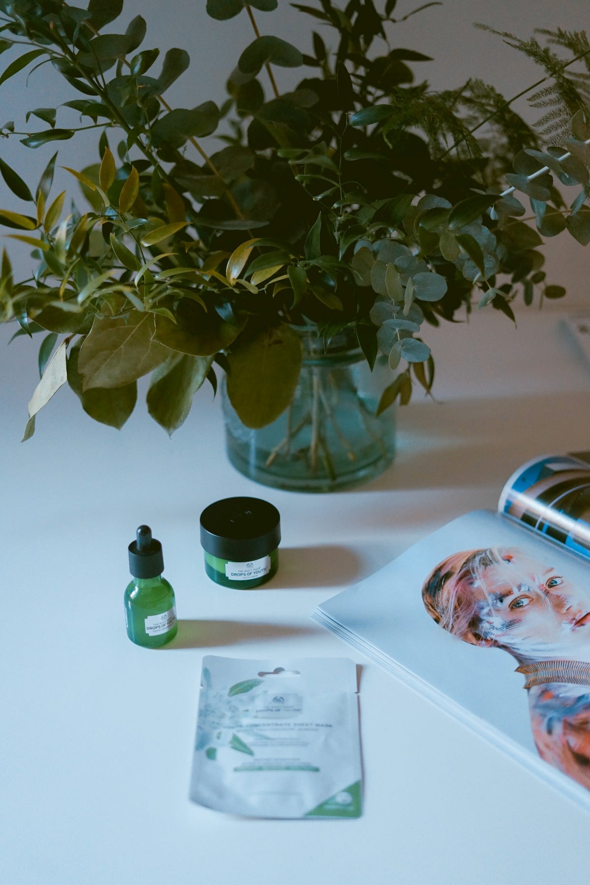 plants in clear vase near open magazine
