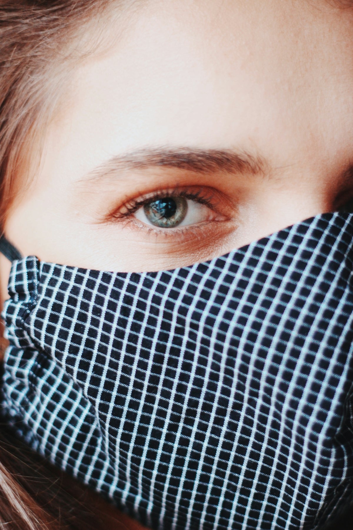 person covering face with white and black plaid textile