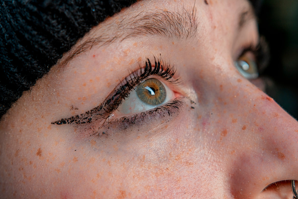 a close up of a woman's eye with a black hat on