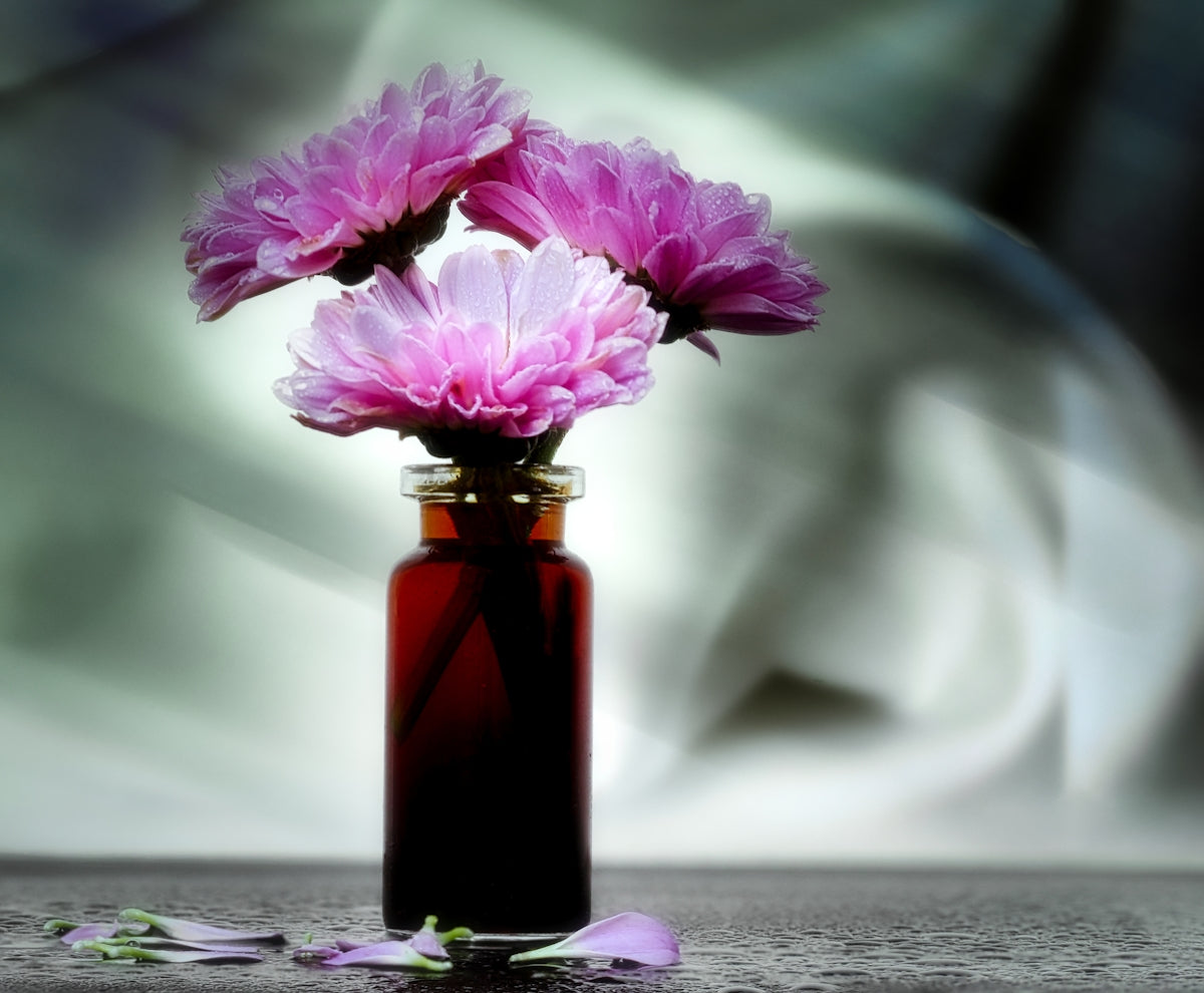 a red vase filled with pink flowers on top of a table