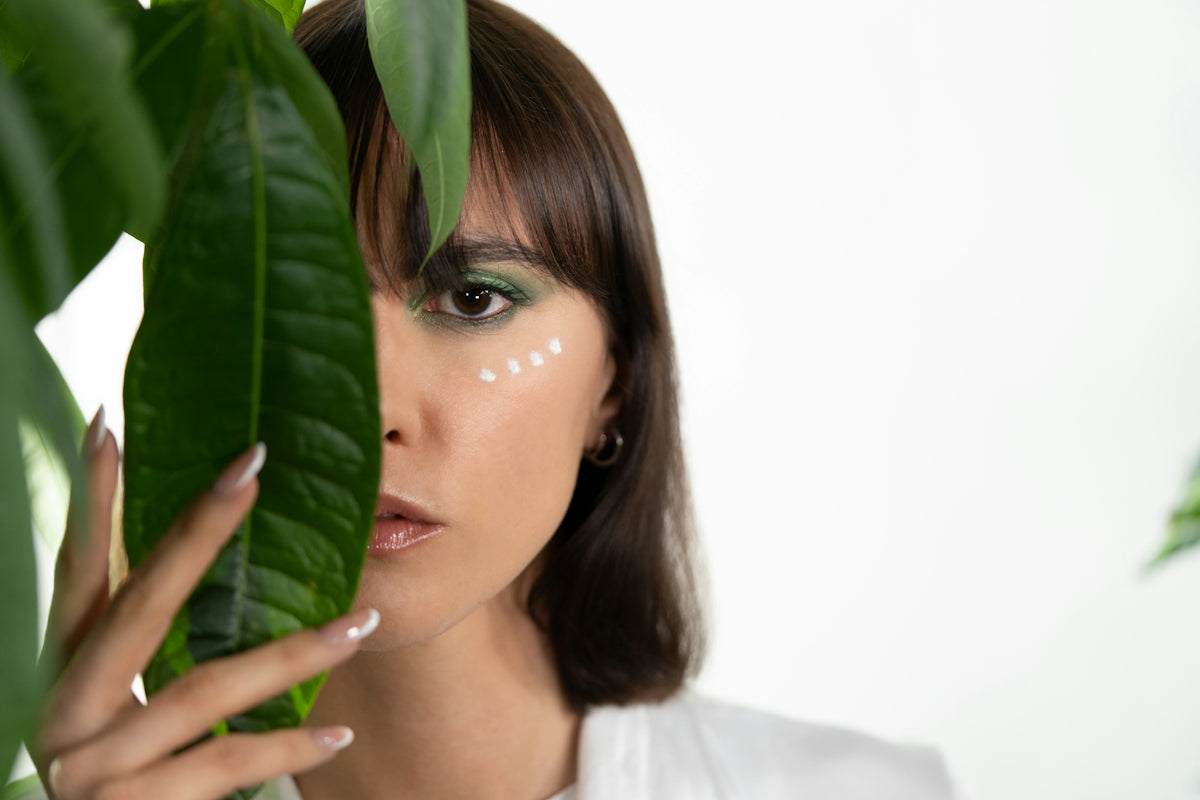 a woman holding a green leaf in front of her face