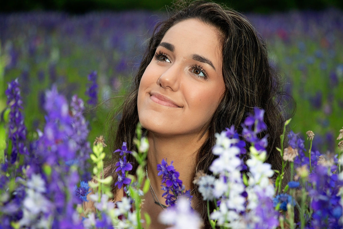 A smiling woman surrounded by wildflowers.