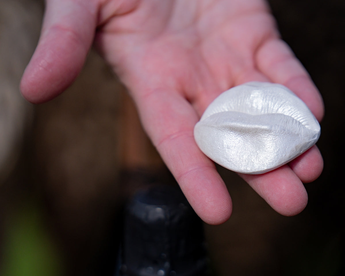 A hand holds a white, lip-shaped object.