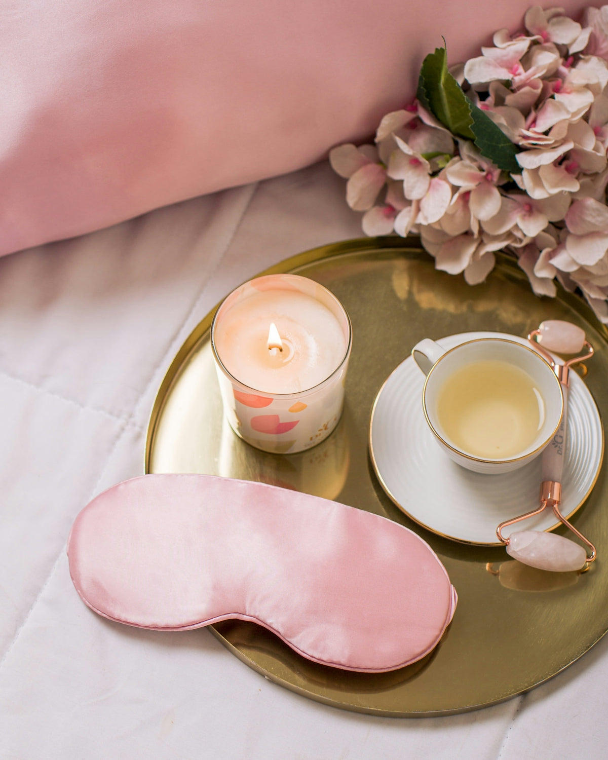 a pink eye mask, a cup of tea and a pink eye mask on a