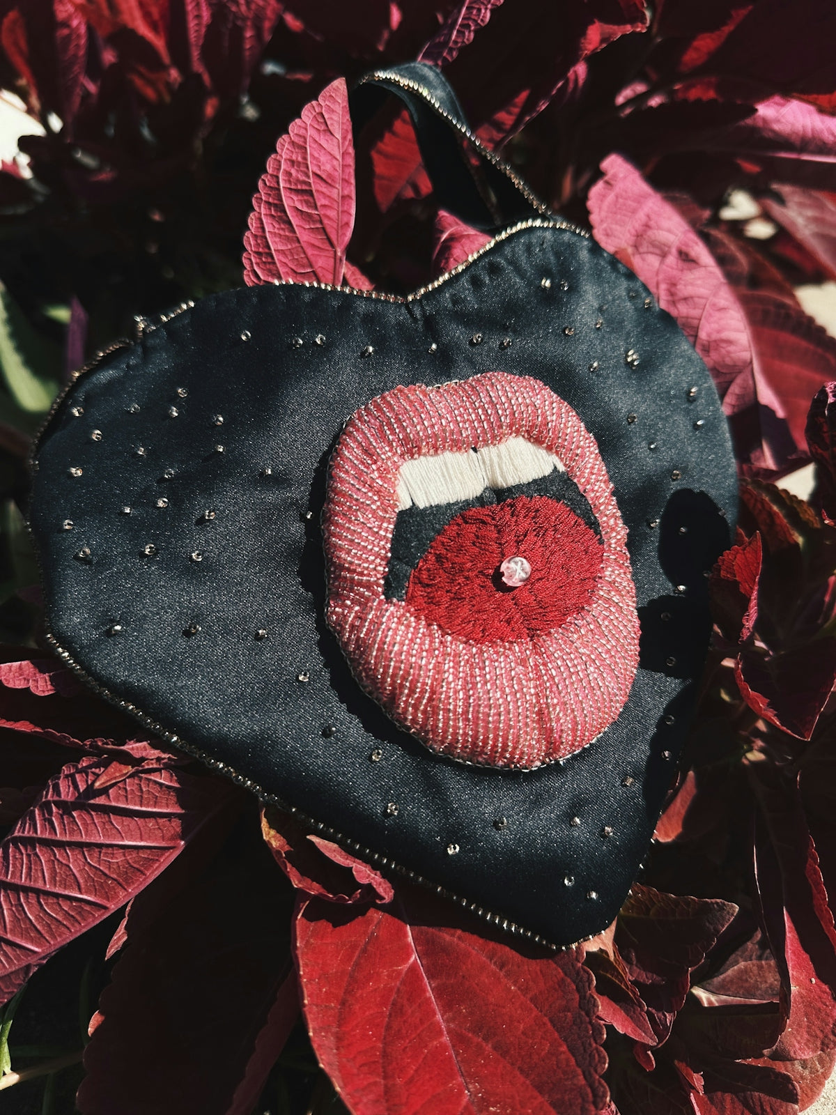 A black purse with a red lip on it