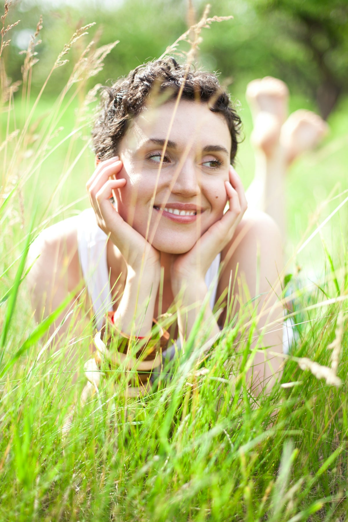 A woman laying in the grass with her hands on her face