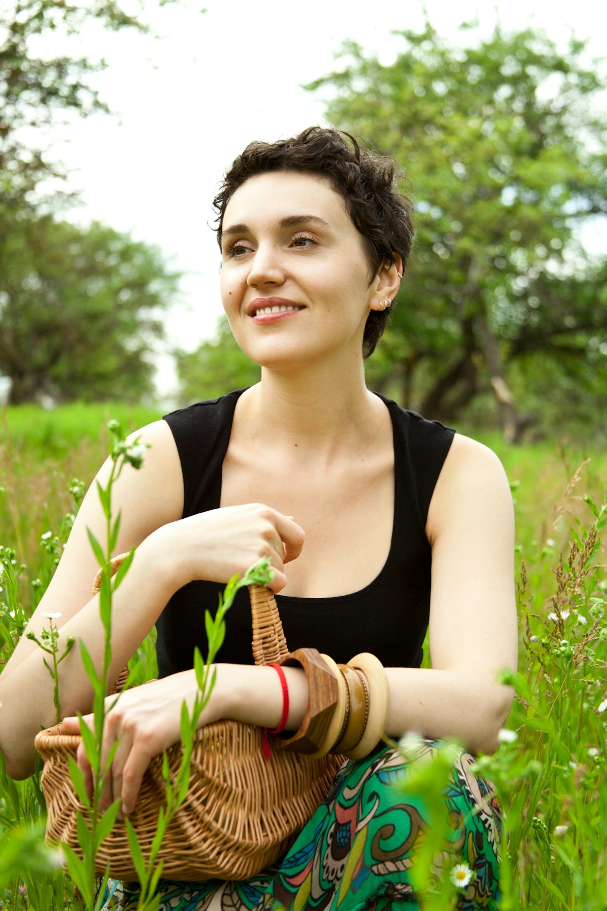 A woman sitting in the grass with a basket