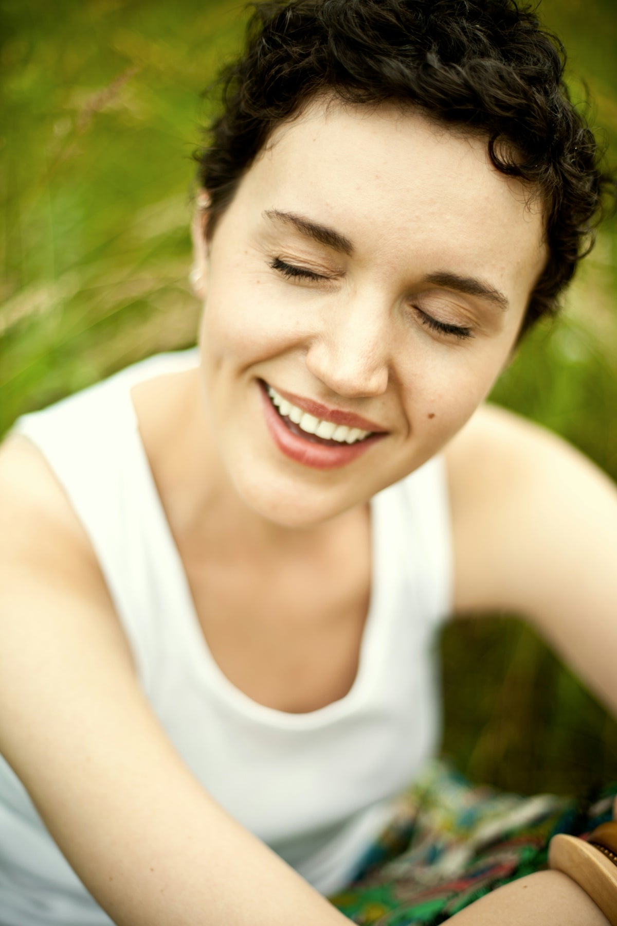 A woman sitting in the grass holding a cell phone