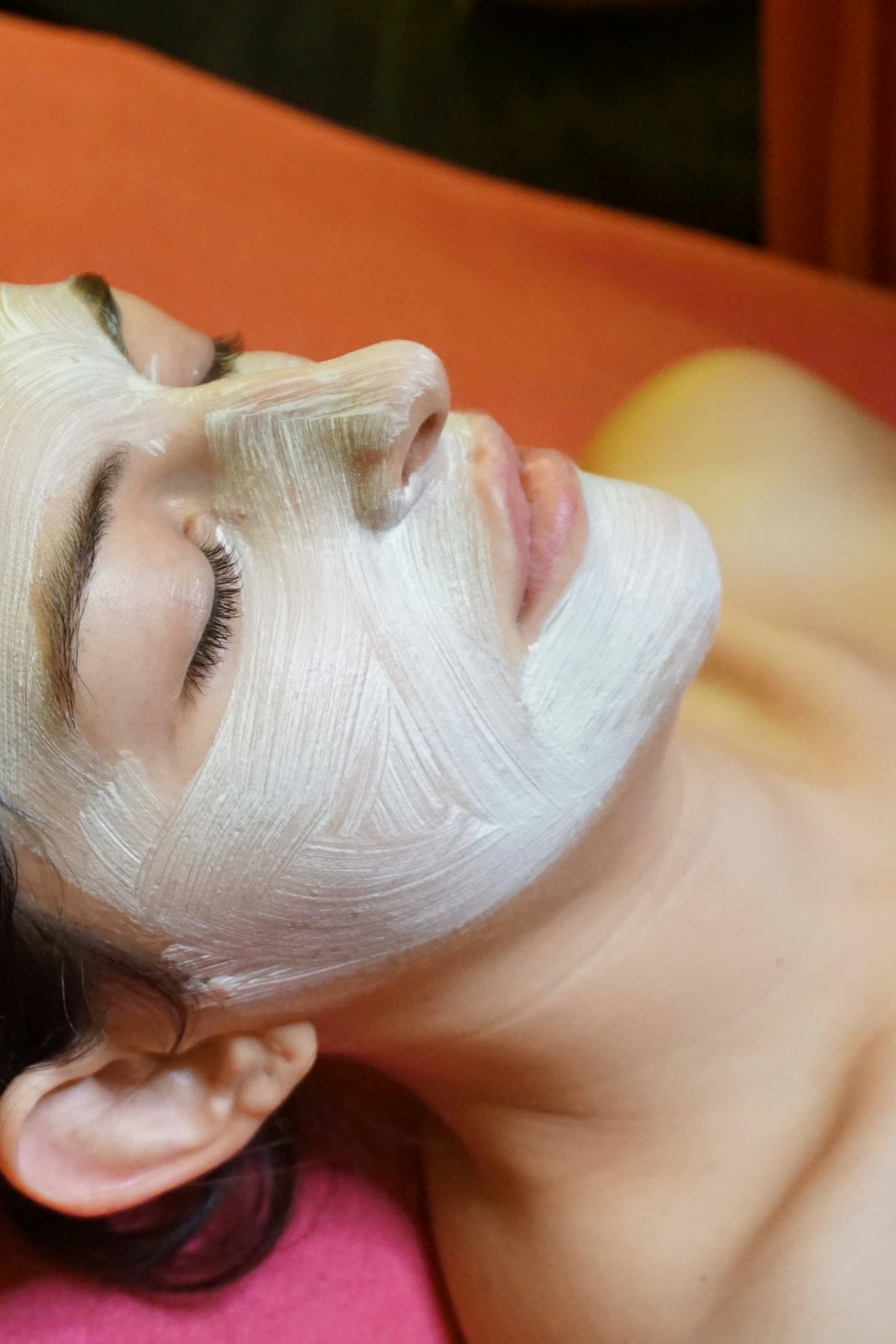 A woman with a facial mask on laying on a bed