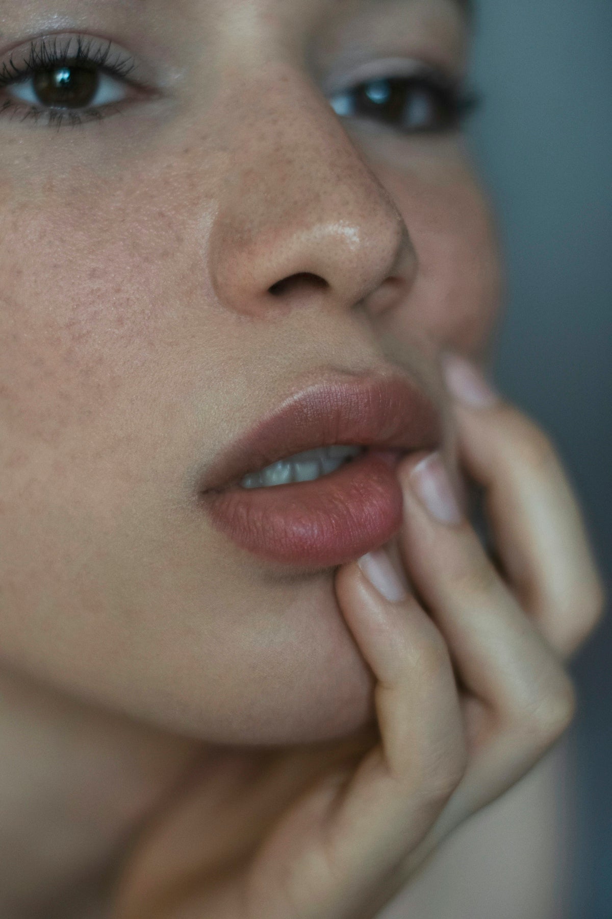 A woman with freckles and her hand on her lips.