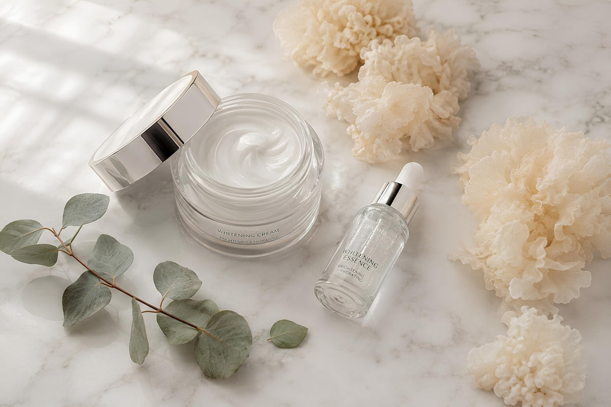 Skincare cream, serum, eucalyptus, and fluffy elements on marble.